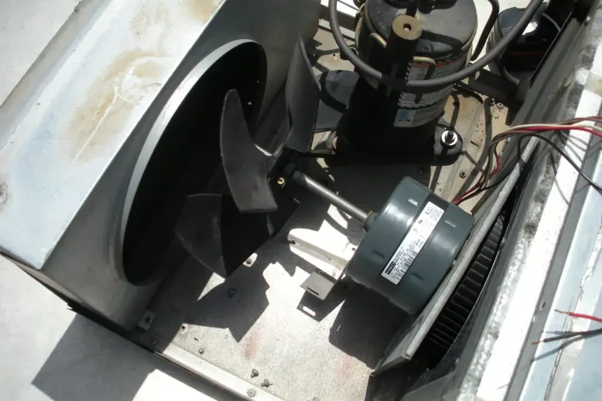 RV camper AC fan assembly with troubleshooting tools beside a rooftop air conditioner