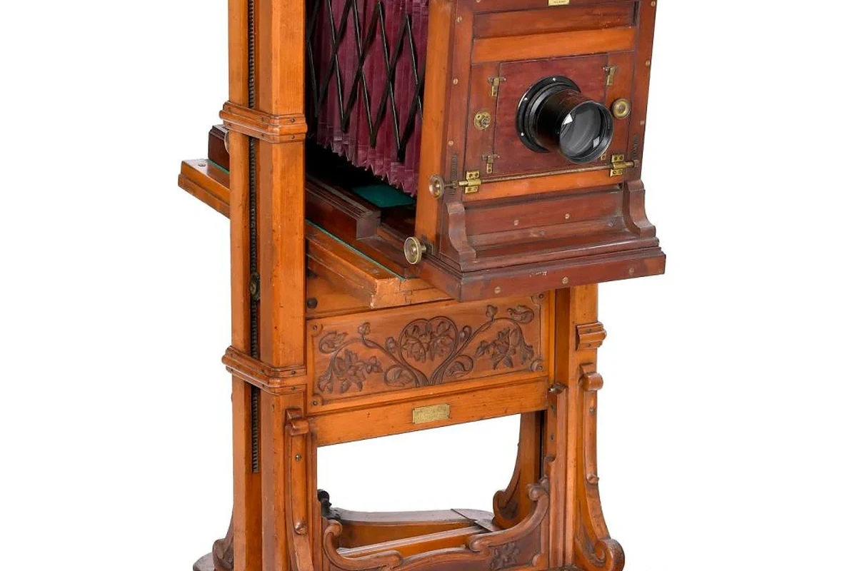 Antique 1890s camera with brass lens, bellows, and wooden body on a studio table