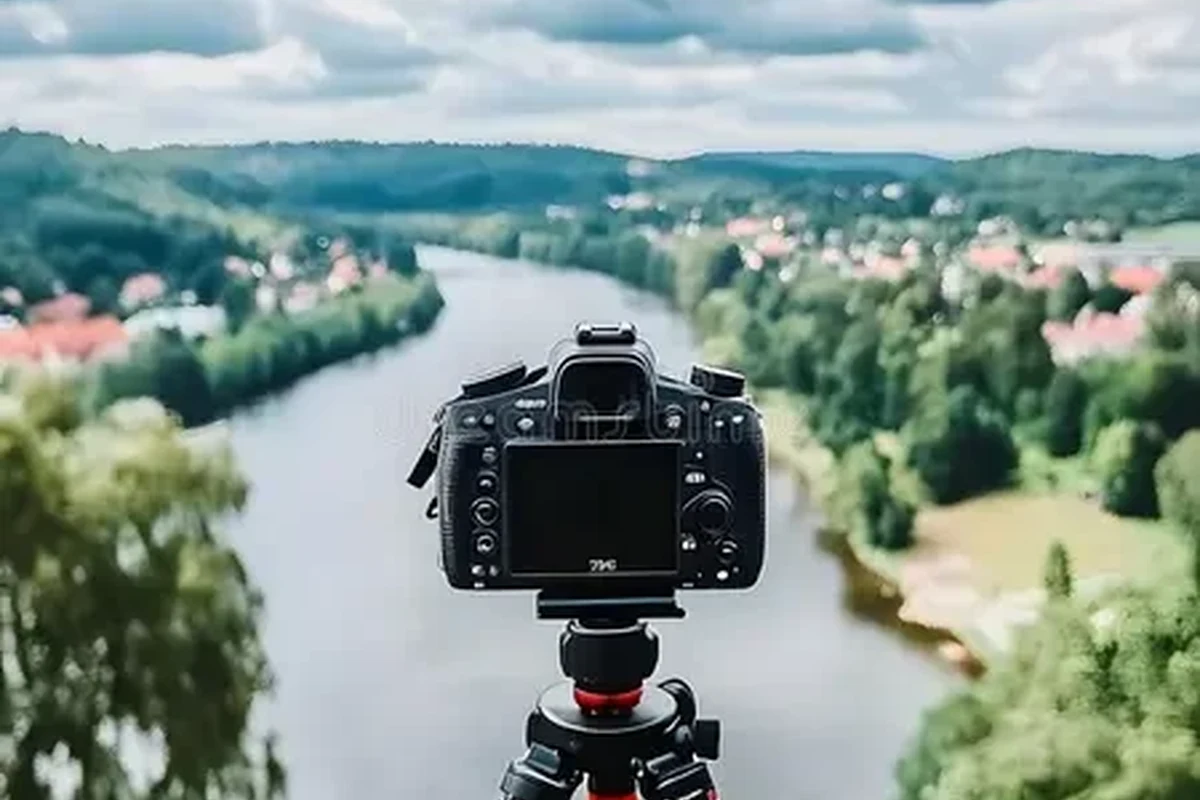 Camera on tripod photographing a river with flowing water and rocky banks at golden hour