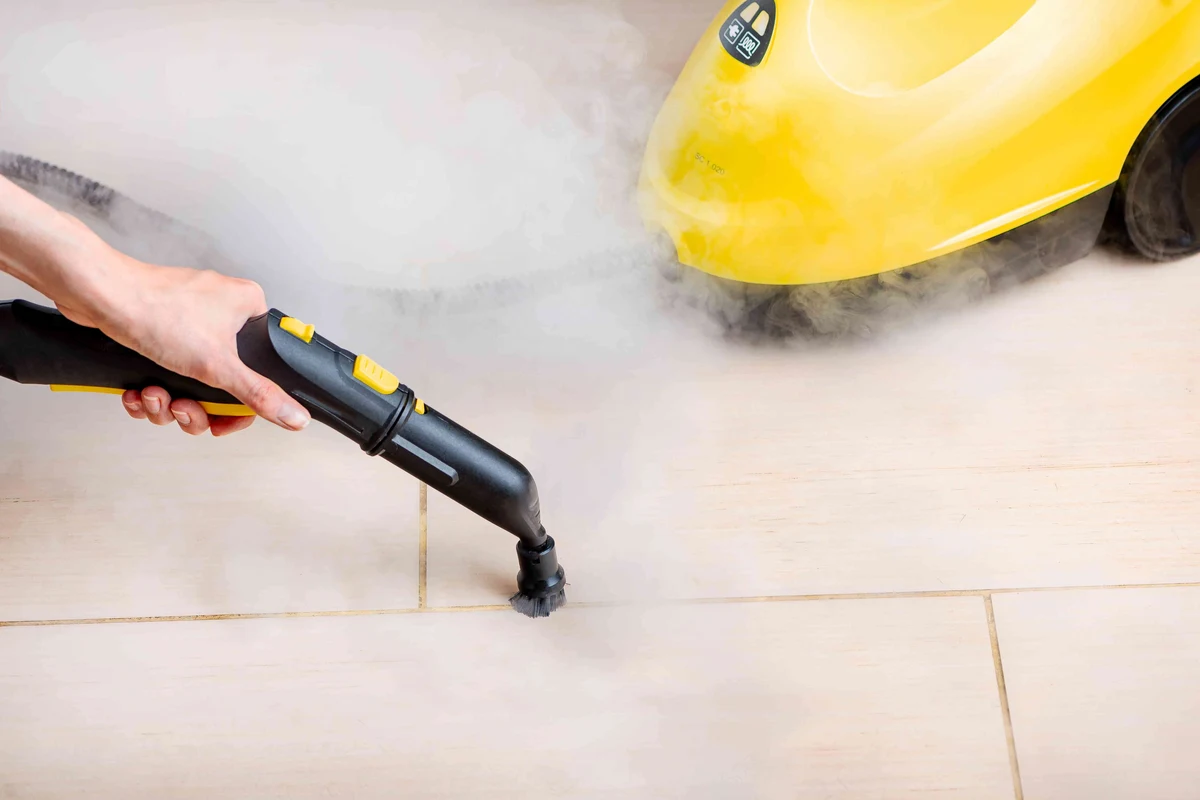 Steam cleaner brush cleaning grout lines on a tiled bathroom floor