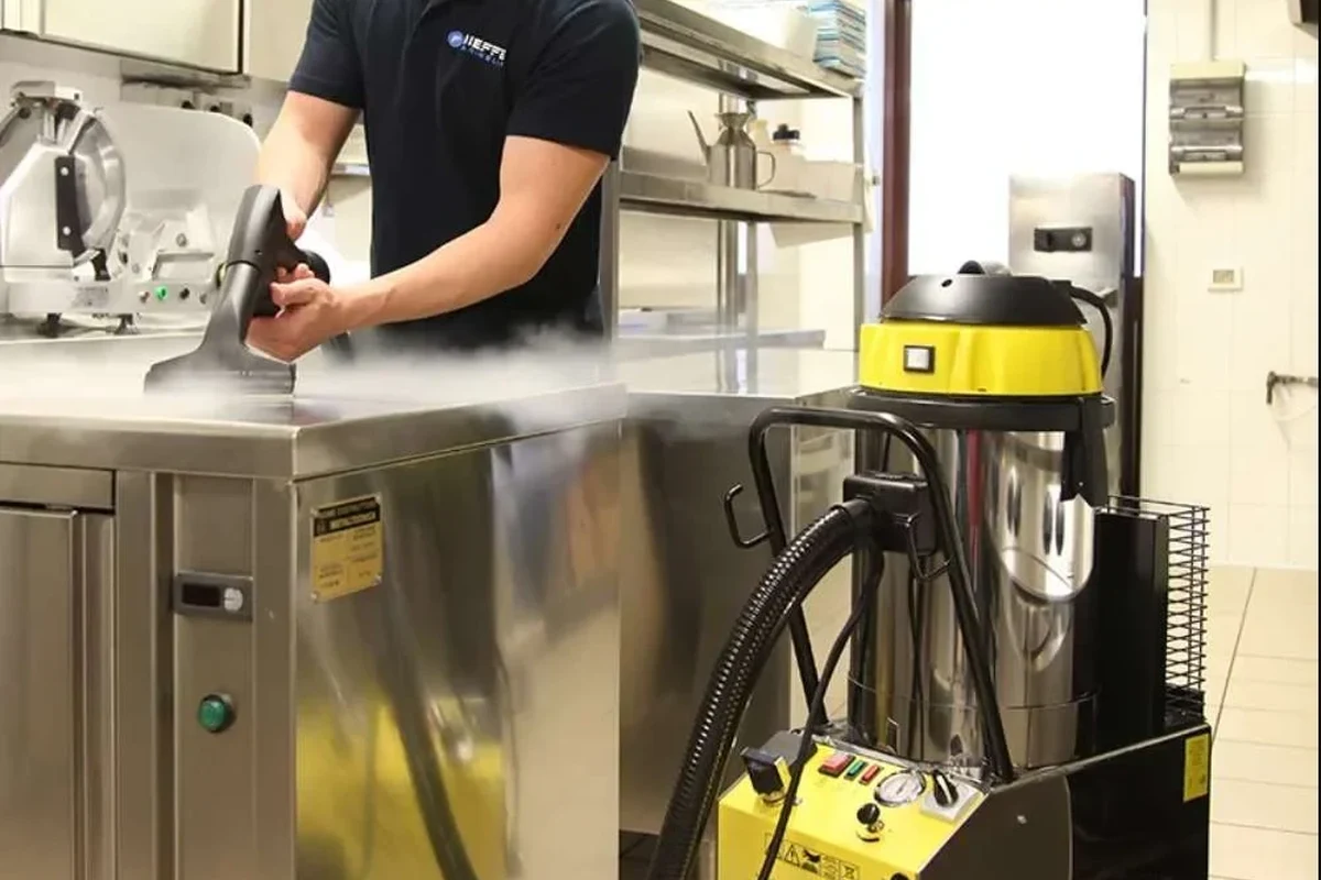 Commercial kitchen steam cleaner removing grease from stainless steel and tiled surfaces