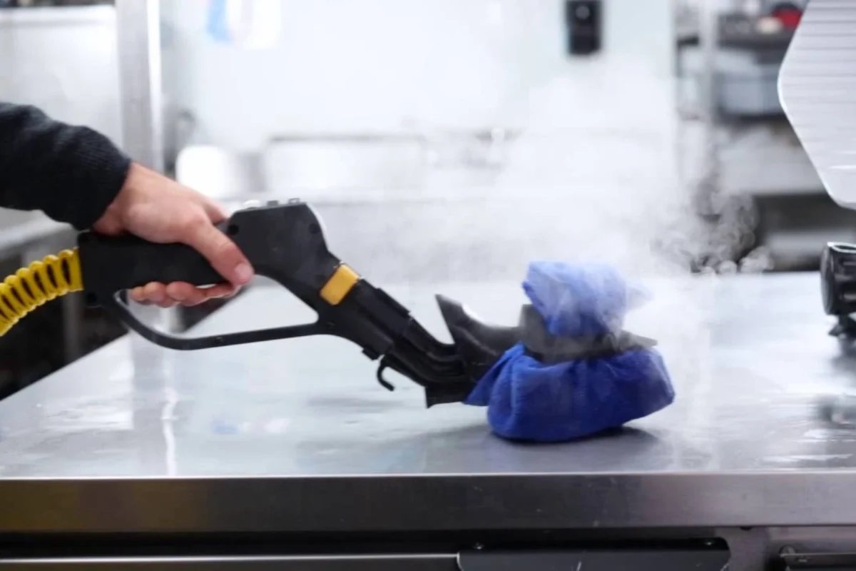 Commercial kitchen steam cleaner removing grease from stainless steel and tiled surfaces