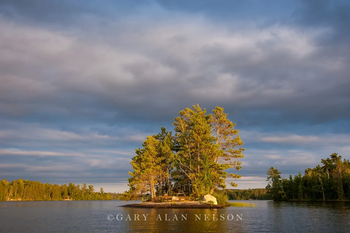 Outdoor lake camera mounted near a dock overlooking calm water and shoreline at sunset