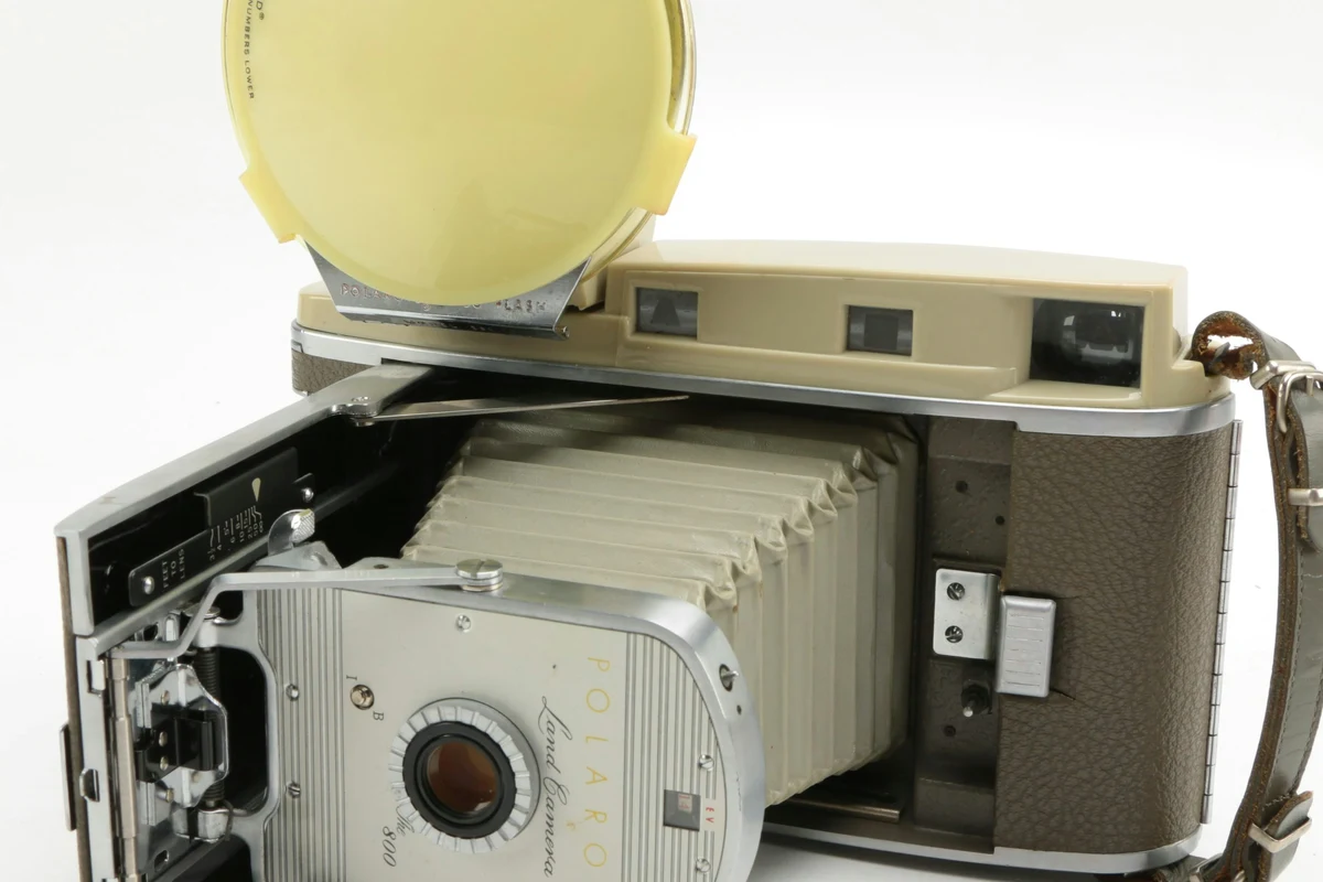 Vintage Polaroid 800 Land Camera on a clean tabletop with film photography accessories