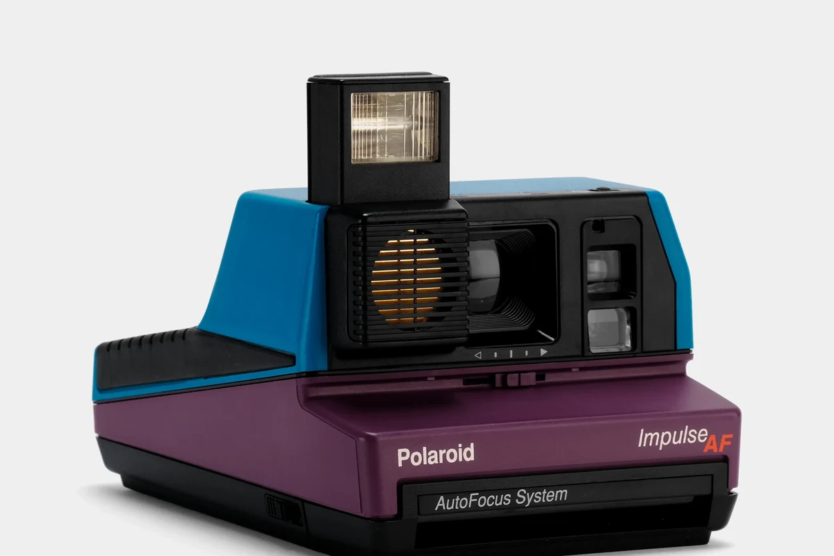Vintage Polaroid Impulse instant camera on a clean tabletop with film and soft natural light