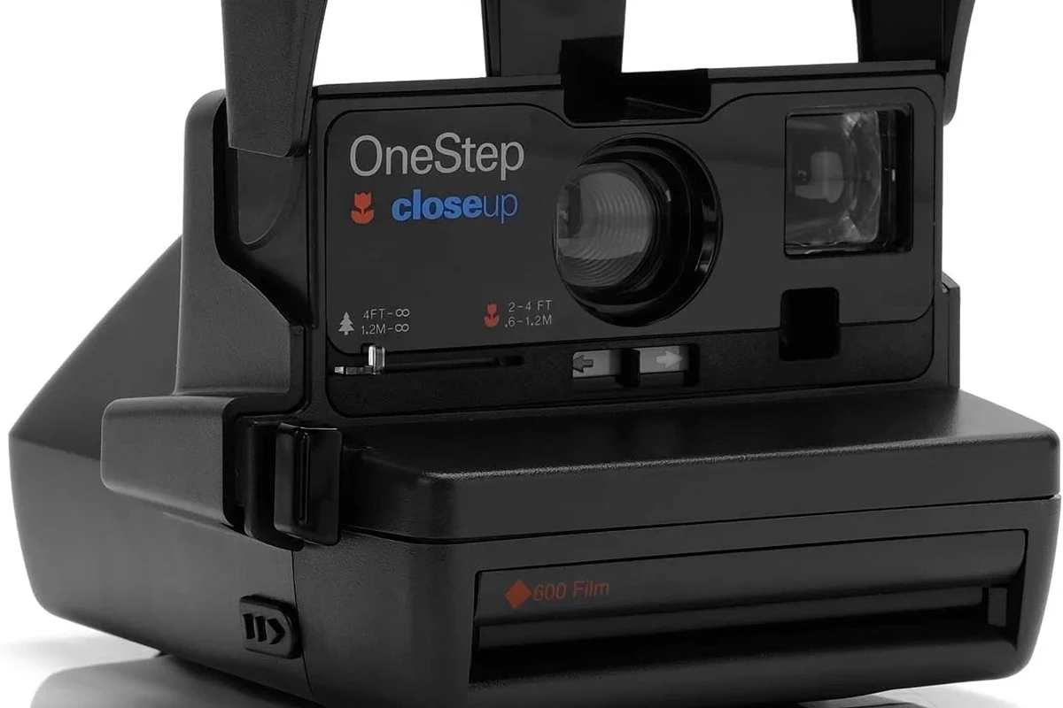 Polaroid OneStep Close Up instant camera on a clean tabletop with film and soft lighting