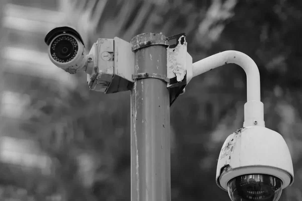 Modern smart home security camera mounted near a front door with app monitoring on a phone