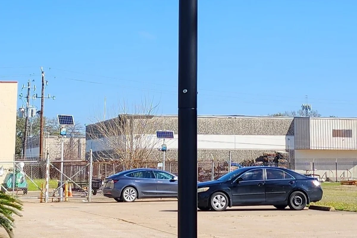 Pole-mounted solar powered security camera overlooking a public street and driveway