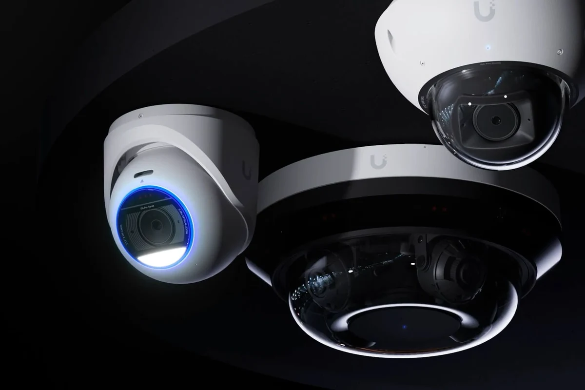 Modern turret security camera mounted under an eave overlooking a home entrance at dusk