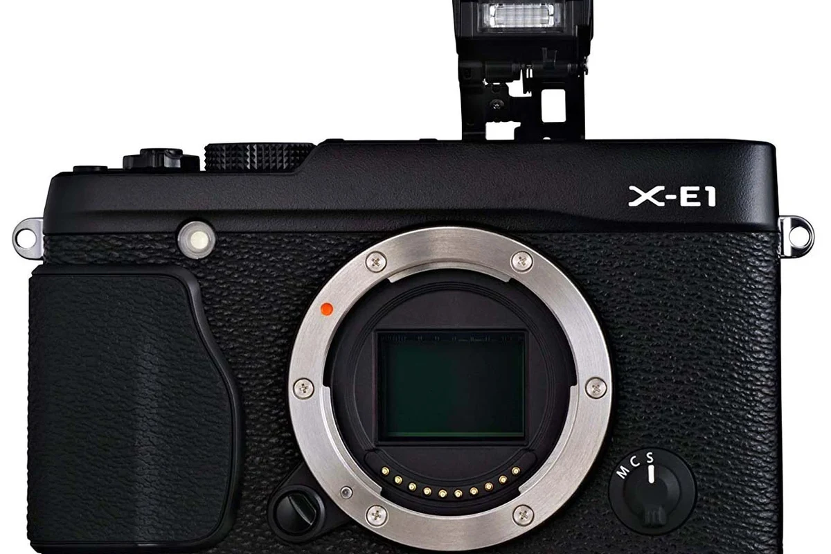 Compact Fujifilm X-E1 mirrorless camera body on a desk with a lens and memory card