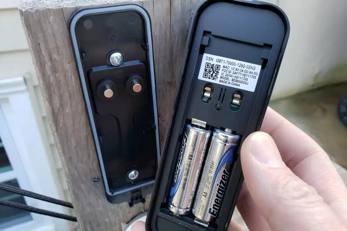 Blink video doorbell battery compartment with two AA batteries and a home entryway background