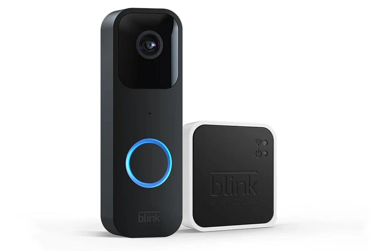 Blink video doorbell mounted by a front door with a smartphone showing the companion app
