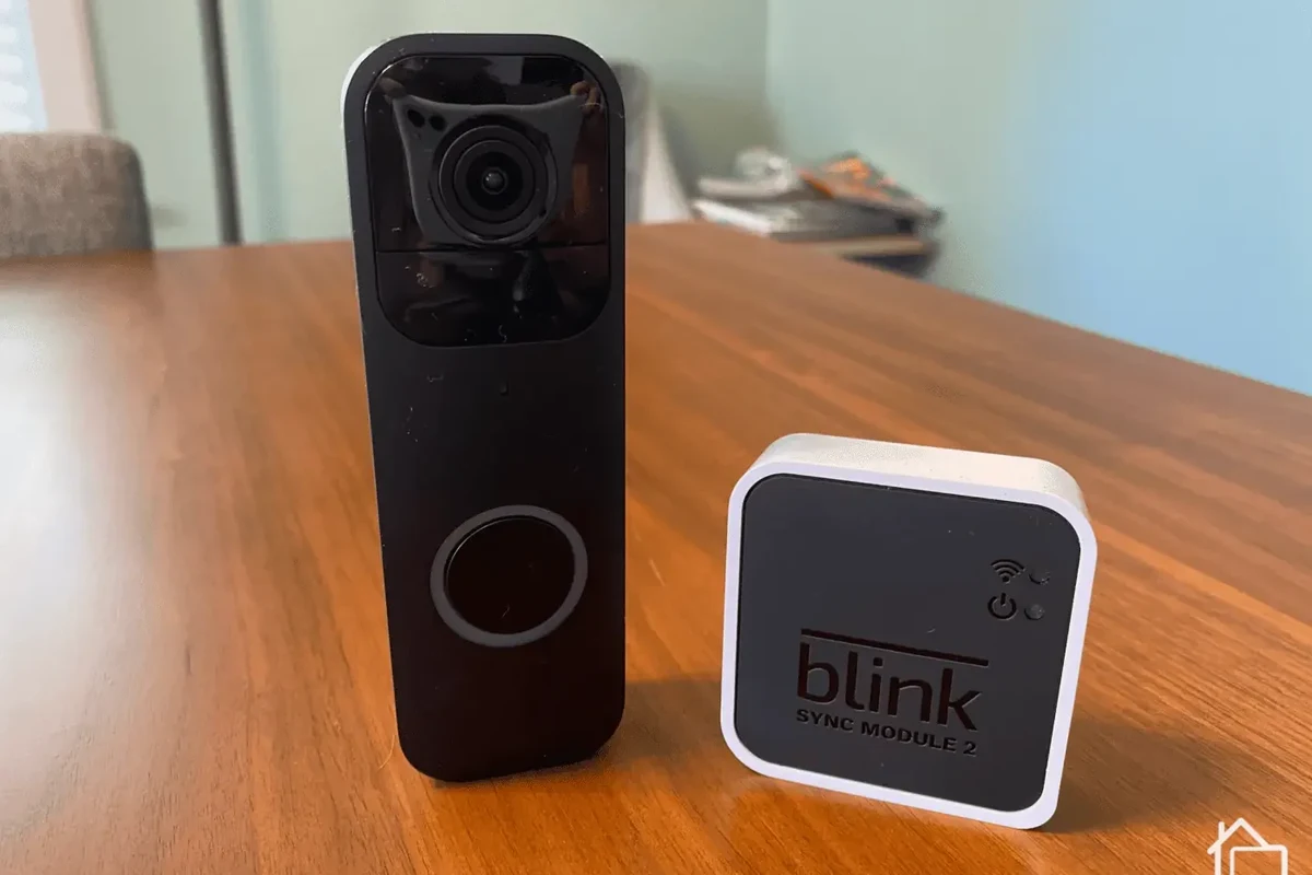 Blink video doorbell mounted outside a home with a smart speaker inside for alerts