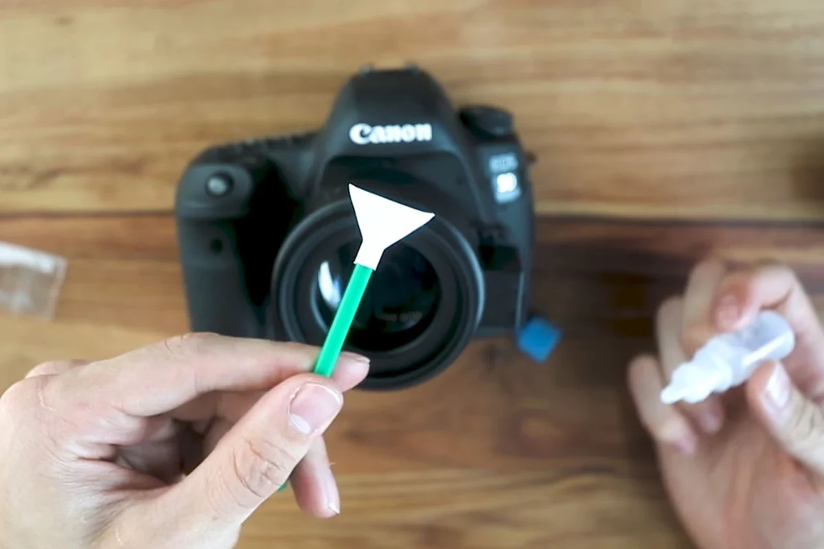 Camera sensor cleaning tools beside a mirrorless camera body on a clean desk