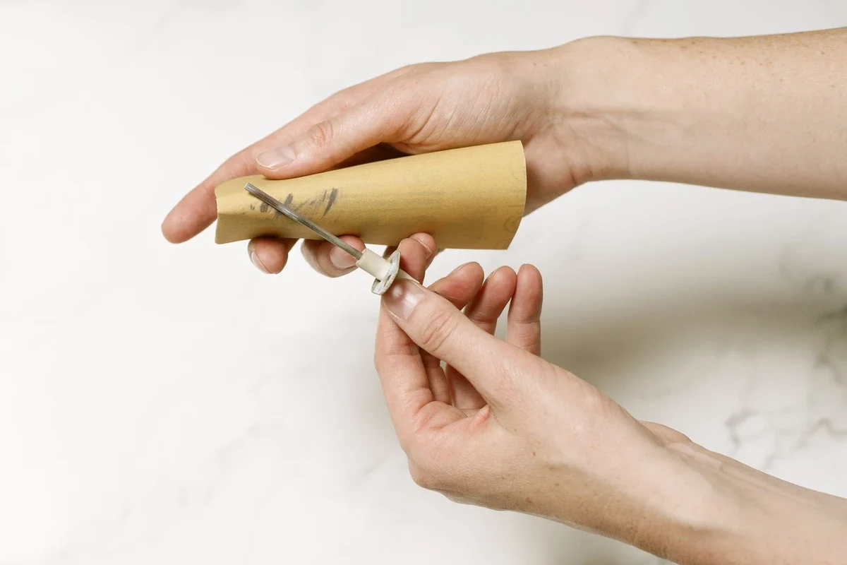 Hand removing a furnace flame sensor for careful cleaning and inspection