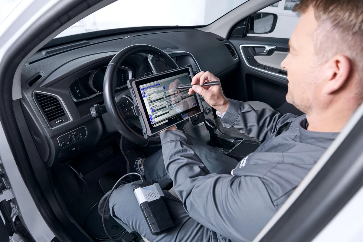 Delphi automotive sensor on a workbench beside wiring connectors and repair tools
