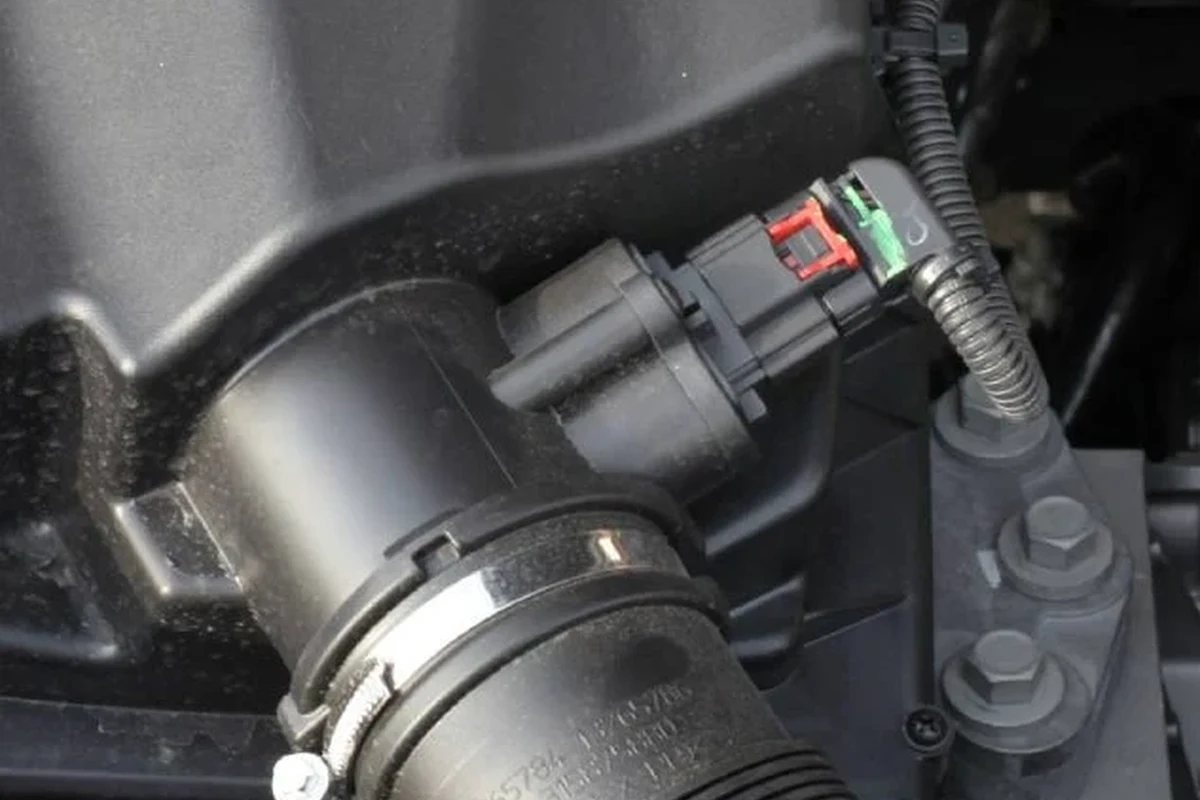 Car engine bay with unplugged mass airflow sensor connector near the intake tube