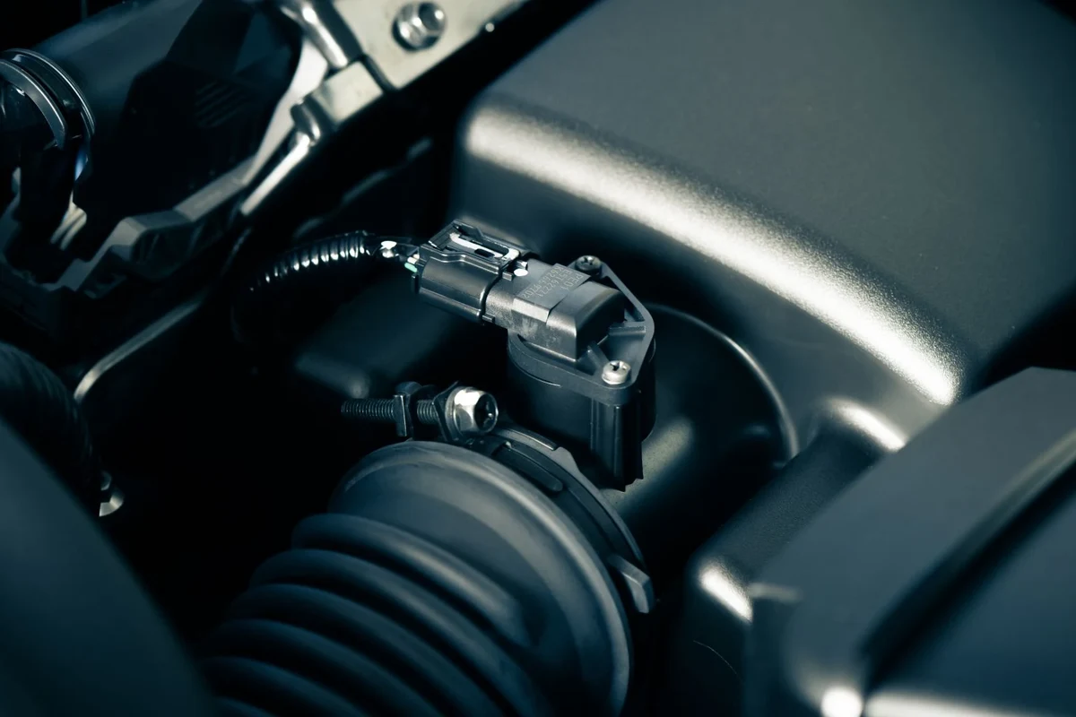 Mechanic inspecting a mass air flow sensor and intake components during engine diagnostics