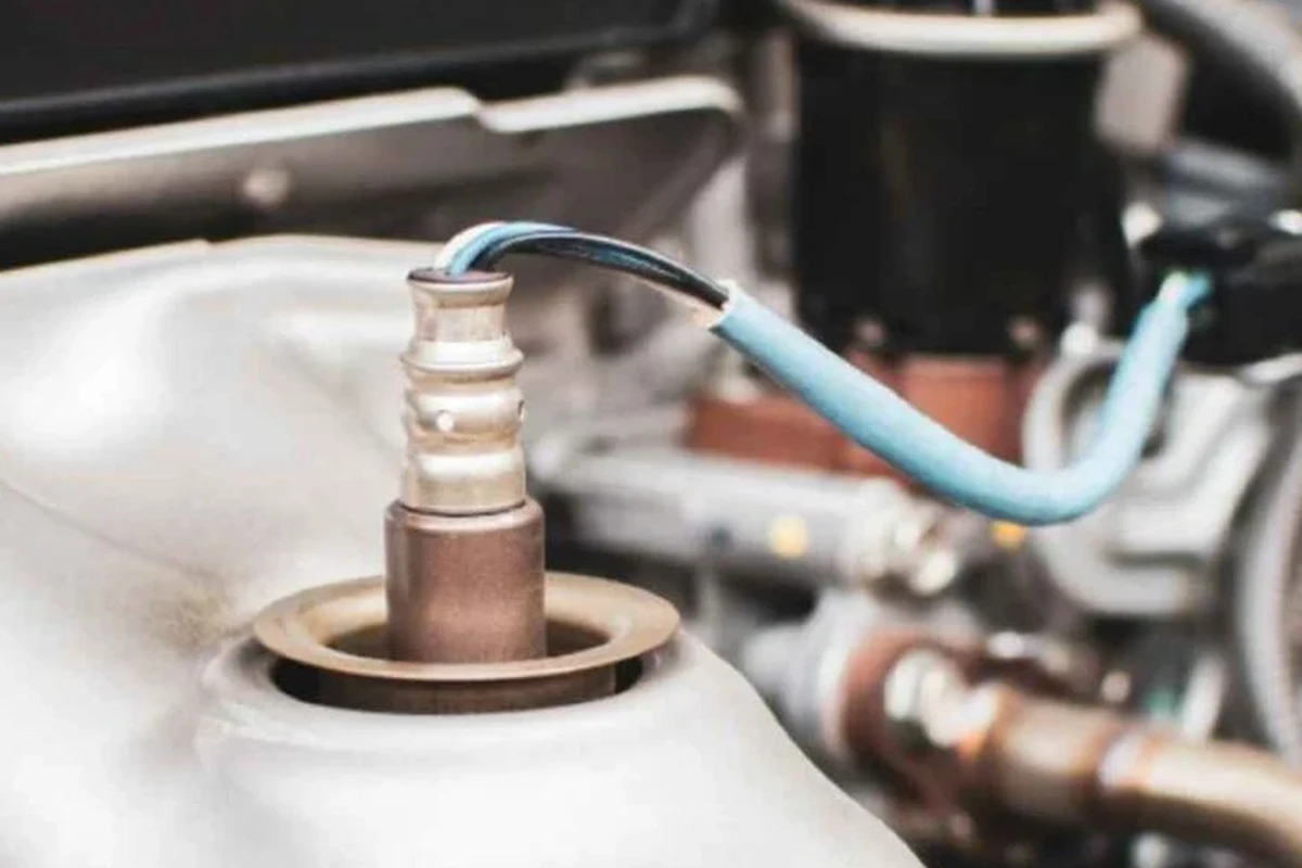 Mechanic-style view of an oxygen sensor and engine bay diagnostic scan tool
