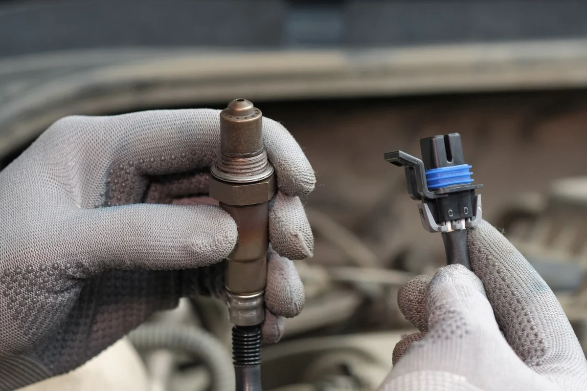 Mechanic scanning a car engine for oxygen sensor trouble using an OBD2 scanner