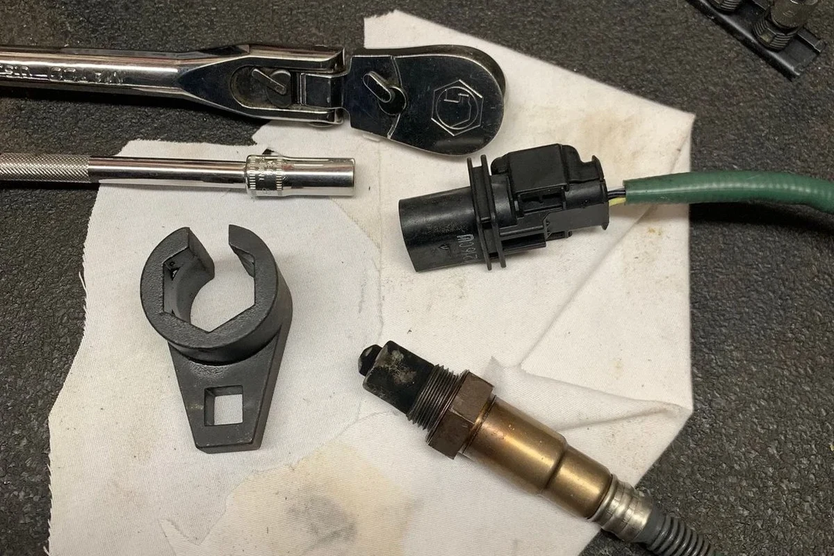 Mechanic removing a stuck oxygen sensor from a vehicle exhaust with a sensor socket