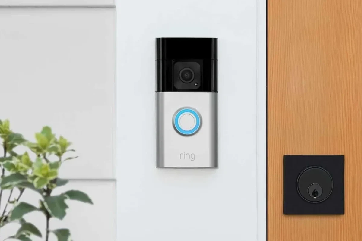 Battery-powered video doorbell mounted beside a front door with a smartphone app nearby