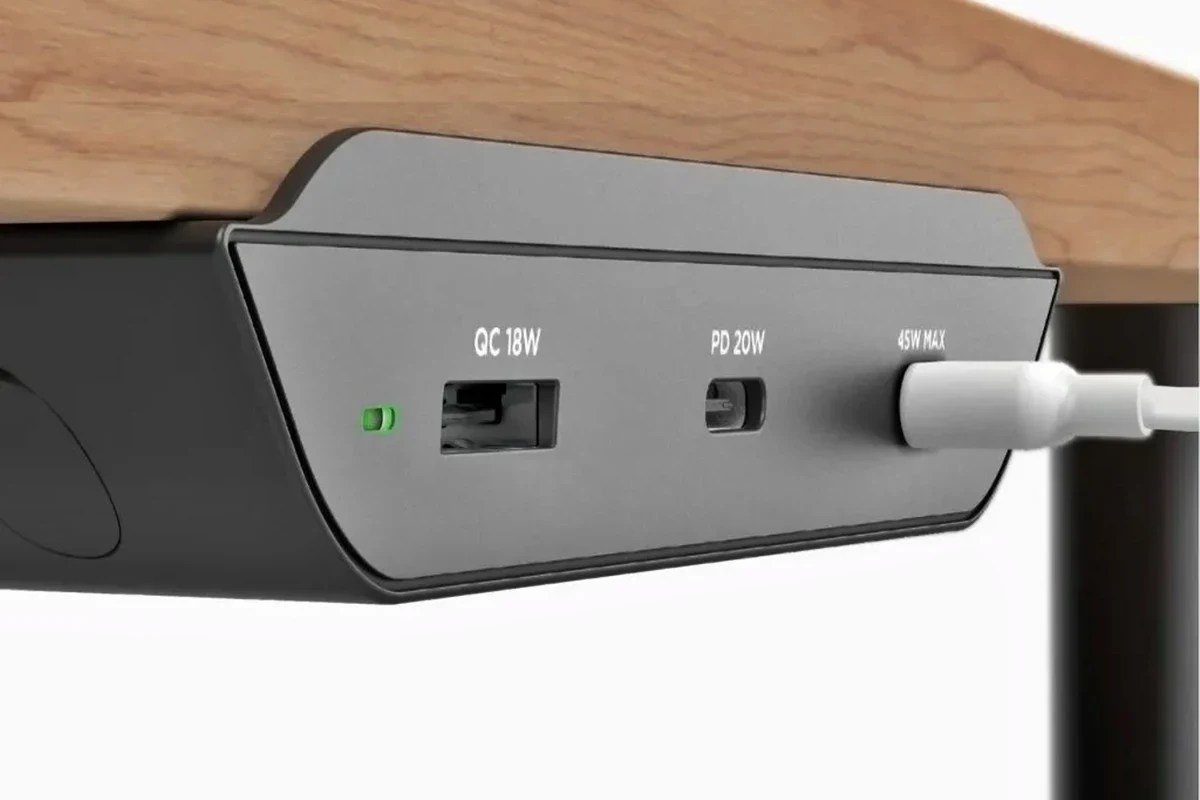 USB-C charging cable connected to a charger beside a laptop and phone